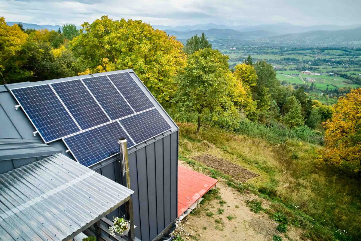 New modern house cottage with solar photovoltaic panel system on roof. Aerial view.
